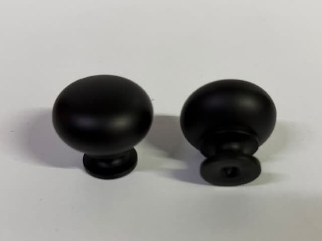 Dos botones negro mate de Cerrajes, uno de frente y otro enseñando su base
